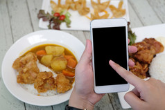 手使用聪明的电话与空白屏幕在模糊食物背景模拟模板食物在线和交付概念