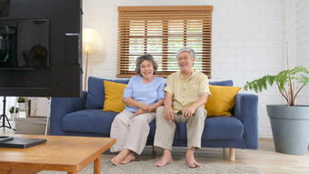 高级亚洲夫妇持有远程控制而看电视首页生活房间与<strong>幸福老人</strong>退休例程生活方式