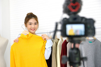 年轻的亚洲女人时尚博主显示布与微笑脸而记录新内容为视频博客和时尚在线购物与相机首页工作室