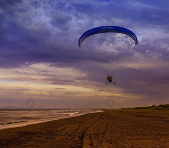 轮廓动力滑翔伞飙升的飞行在的海对日落天空的轮廓动力滑翔伞飙升的飞行在的海对日落天空