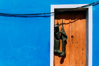 一对长筒靴靴子挂从棕色（的）乡村门口与明亮的蓝色的墙外观复制空间一对长筒靴挂从棕色（的）乡村门口与明亮的蓝色的墙外观复制空间