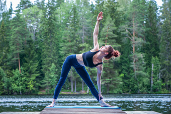 瑜珈女孩练习瑜伽做乌蒂塔特里科纳萨那锻炼扩展三角形构成的湖的概念绥靖政策健康的生活方式