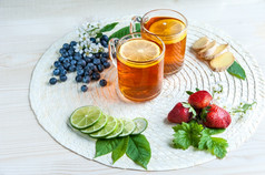 茶背景茶透明的杯子与柠檬柠檬酸橙薄荷樱桃花朵时尚的色彩斑斓的背景食物行业茶包装餐厅业务