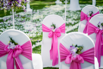 的婚礼<strong>聚会</strong>地点的椅子与白色草坪上<strong>封面</strong>装饰粉红色的主题与的锥玫瑰和帕特尔斯为扔在的新结合他们的走的过道婚礼宴会椅子白色和粉红色的他们锥玫瑰花瓣