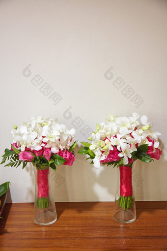 婚礼花束为的新娘和伴娘夫妇新鲜的红色的粉红色的玫瑰和白色花装修与红色的粉红色的丝带的长玻璃花瓶木地板上