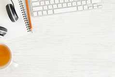 平躺照片办公室桌子上与耳机和键盘复制空间白色背景与笔记本和铅笔茶前视图