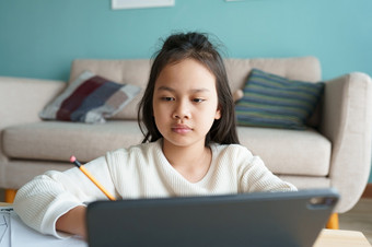 教育亚洲女孩学习与在线导师通过的互联网平板电脑数字首页早....亚洲孩子们看电脑和写家庭作业概念在线学习首页