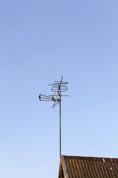 金属天线为接收电视信号安装的屋顶私人房子对蓝色的天空电视天线屋顶