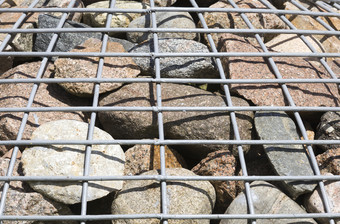金属网格后面哪一个在那里大数量鹅卵石和石头特写镜头装饰的城市一些种类强化石头金属网格