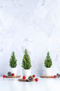 三个圣诞节树与松锥和装饰圣诞节球白色表格和大理石瓷砖墙backgroundclean最小的简单的styleholiday仍然生活模型横幅与空间添加文本