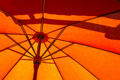 特写镜头的结构的橙色海滩伞使木为受保护的阳光