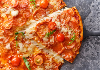 片意大利辣香肠披萨与樱桃西红柿切片美味的意大利辣香肠披萨的灰色石头背景前视图特写镜头