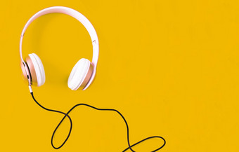 粉红色的耳机和黑色的电缆<strong>柔和</strong>的颜色黄色的<strong>背景音乐</strong>概念空白复制空间