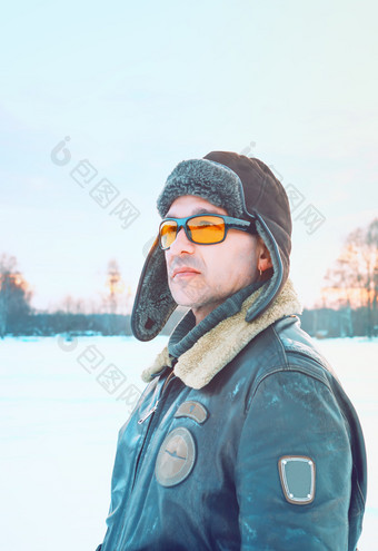 肖像男人。穿飞行皮革夹克与他和黄色的眼镜对模糊背景雪场和天空古董飞行员风格古董肖像男人。飞行夹克和他