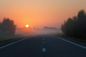 废弃的直沥青路消失了成的早....雾黎明的金磁盘的太阳上升<strong>万里</strong>无云的橙色天空日出的早期多雾的早....