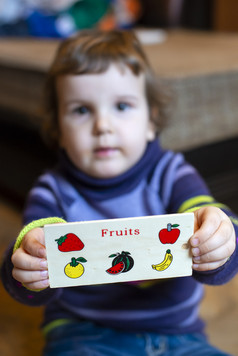 小女孩显示董事会与水果画孩子玩与木水果玩具健康的吃概念上的比喻与画水果