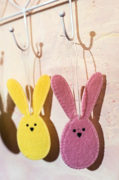 复活节兔子钩状的的墙房间多彩色的复活节兔子使织物粉红色的墙硬光从窗口和阴影的墙白色古董悬挂器
