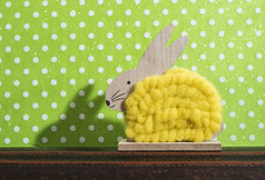 黄色的复活节兔子前面墙点房间兔子装饰和绿色壁纸背景点影子兔子的墙木兔子数字形状和黄色的纱极简主义概念