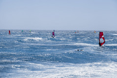 集团冲浪板练习的海洋与色彩斑斓的帆