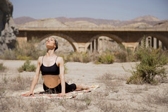 年轻的活跃的女人练习瑜伽沙漠阳光明媚的一天健康和活跃的生活概念