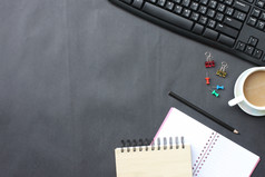 黑色的桌子上与咖啡杯键盘笔记本和笔放置的officetop视图和有复制空间的概念你的工作