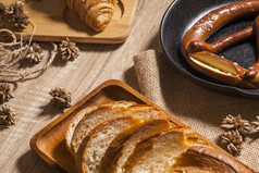 新烤面包这两个羊角面包法国面包和椒盐卷饼放置托盘和切董事会和木表为客户服务