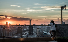 曼谷泰国7月年轻的女人放松屋顶阳台与俯瞰的城市黎明视图新早....模糊小镇背景复制空间焦点具体地说