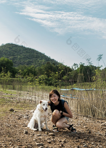 视图年轻的亚洲女人与白色狗享受和平时刻美丽的视图湖海岸与山范围背景宠物和女人休息和享受生活方式焦点具体地说