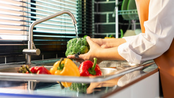 女人手洗蔬菜为准备素食主义者沙拉的工作台附近水槽<strong>现代厨房</strong>自制的健康的食物概念