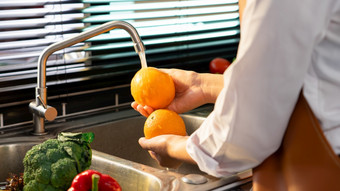 女人手洗蔬菜为准备素食主义者沙拉的工作台附近水槽<strong>现代厨房</strong>自制的健康的食物概念