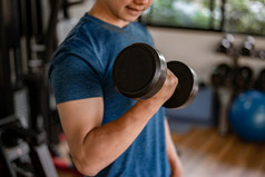 培训健身房概念年轻的成人使用他的肌肉发达的强大的手臂提升哑铃向上和向下的健身房