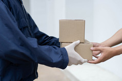包裹交付概念的邮递员白色橡胶手套和光重量黑暗蓝色的外套将两个小包裹的帖子他的客户端