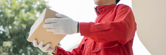 包裹交付概念的邮差穿红色的统一的和手套从一些<strong>物流公司</strong>将的包裹客户在科维德流感大流行