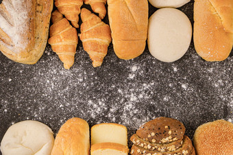 面包概念饼面包面包片面包与种子和羊角面包安排的黑暗背景与冰冷的洒