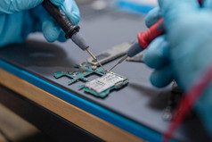 电话修复概念年轻的电技术员使用安培表测量的当前的电路电子设备