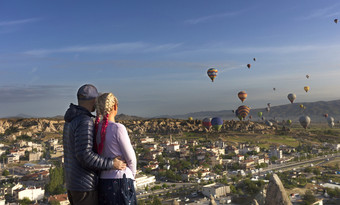年轻的人看几十个气球飞行在的山谷卡帕多西亚黎明中央火鸡年轻的夫妇手表几十个气球飞在的山谷卡帕多西亚