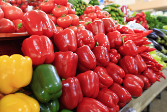 不同的品种红色的黄色的和绿色贝尔辣椒的背景模糊的黄瓜菠菜和其他蔬菜是出售托盘的市场五彩缤纷的甜蜜的辣椒西红柿黄瓜茄子和其他蔬菜出售的市场