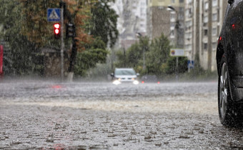 暴雨雨十字路口和红色的光反映了的流水城市街暴雨雨的路和的人行道上浇水汽车站的十字路口