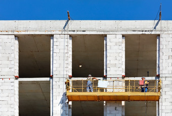 建设摇篮与工人的墙房子下建设的暂停电平台可靠的为安全工作高度建设工人爬摇篮沿着的外观建筑下建设