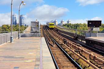 开放部分的铁路跟踪地铁桥基辅沿着哪一个黄色的地铁火车冲对背景城市景观和蓝色的天空前景轻微的模糊为复制空间的地铁火车冲通过的地铁桥基辅的左一边的城市