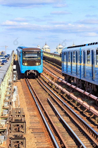 地铁桥基辅沿着哪一个两个地铁火车冲对每一个其他每一个它的自己的一边对的背景阳光明媚的一天和蓝色的天空复制空间垂直图像两个地铁火车旅行Rails对每一个其他沿着的基辅地铁桥在的Dnipro河