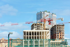 monolithic-frame混凝土结构和长塔起重机的建设多层住宅建筑对的蓝色的天空后面绿色金属栅栏复制空间城市景观建设多层建筑使用现代方法单片框架技术