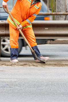路工人明亮的橙色反光统一的铲子沙子和删除碎片从的路垂直图像复制空间路服务工人擦伤的积累沙子和碎片与铲垂直图像