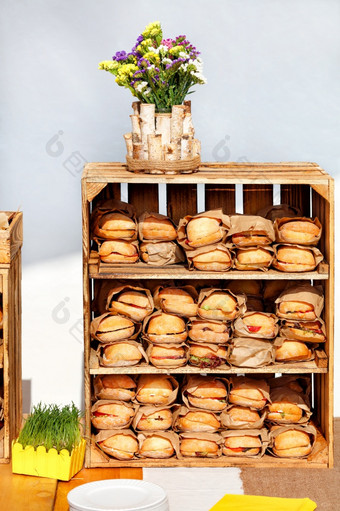 集团自制的汉堡是包装工艺纸和排货架上木盒子的阳光下一个桩白色盘子和装饰能绿色草复制空间街食物汉堡是包装工艺纸的货架上木盒子
