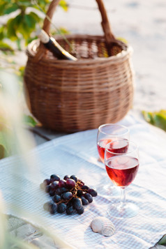 两个酒眼镜与红色的酒站布海滩旁边葡萄和柳条篮子与瓶酒