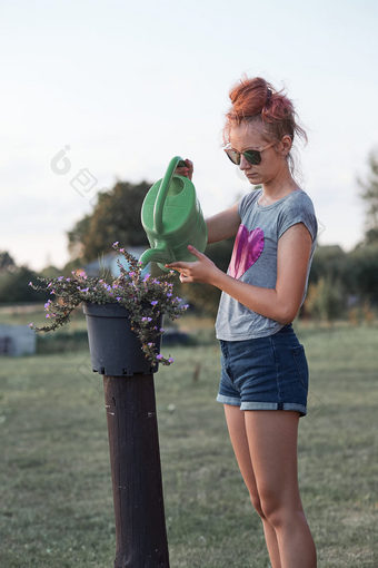 十几岁的女孩帮助水的花日益增长的花能倒水从绿色浇水可以工作后院日落坦诚的人真正的时刻真实的的情况下