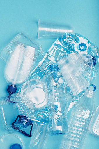 压扁空塑料瓶杯包装市场袋和帽在蓝色的背景收集塑料浪费回收概念塑料污染和太许多塑料浪费复制空间的前