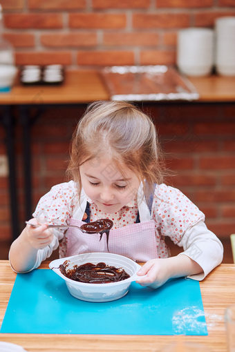 小女孩闻的融化了巧克力和可可孩子采取部分烘焙车间烘焙类为孩子们有抱负的小厨师学习烹饪结合和激动人心的准备成分真正的人真实的的情况下