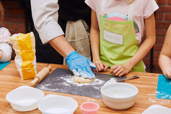 女孩与厨师帮助揉捏的面团为烘焙的蛋糕孩子采取部分烘焙车间烘焙类为孩子们有抱负的小厨师学习烹饪结合和激动人心的准备成分真正的人真实的的<strong>情况</strong>下