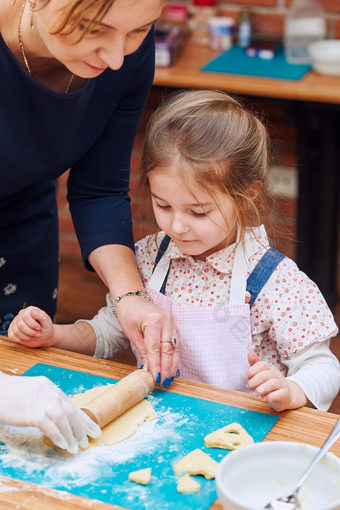 小女孩滚动的面团与她的妈妈rsquo帮助为的饼干切割的面团心形状孩子采取部分烘焙车间烘焙类为孩子们有抱负的小厨师学习烹饪结合和激动人心的准备成分真正的人真实的的情况下